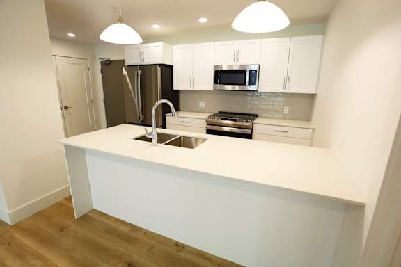 A kitchen with a white countertop and stainless steel appliances.