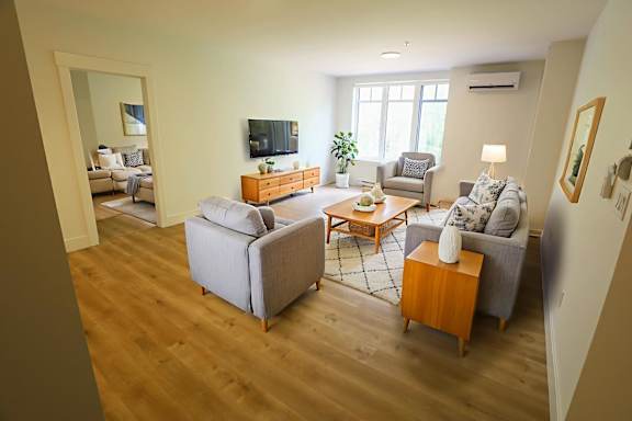 A living room with a grey couch, a wooden side table, and a television.