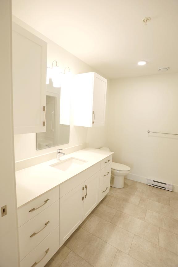A white bathroom with a sink, toilet, and a mirror.