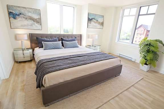 A bedroom with a large bed and a potted plant.