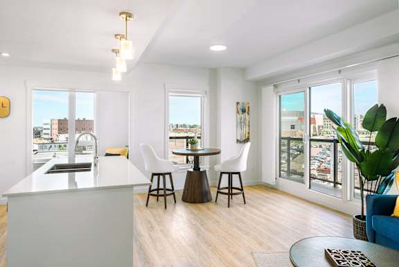 A modern kitchen with a bar area and a dining table with chairs.