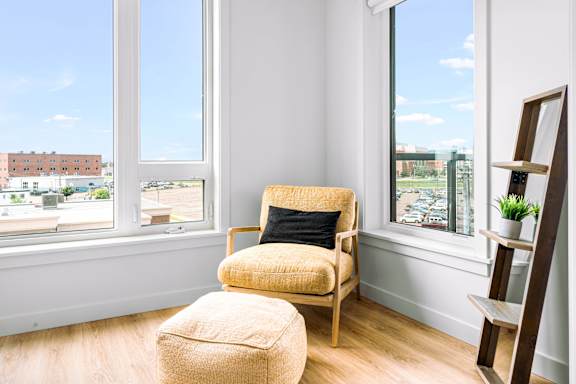 A chair and ottoman are in a room with a window overlooking a city.