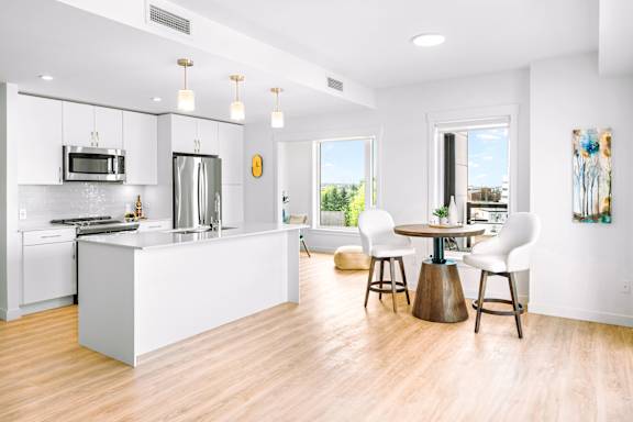 A modern kitchen with a white island and bar stools.