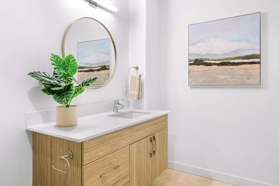 A bathroom with a sink, mirror, and a painting on the wall.