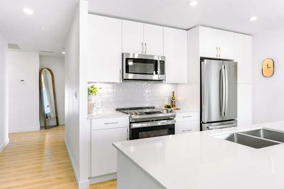 A modern kitchen with a white countertop and stainless steel appliances.