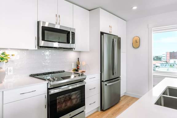 A kitchen with a stainless steel refrigerator and microwave above the stove.