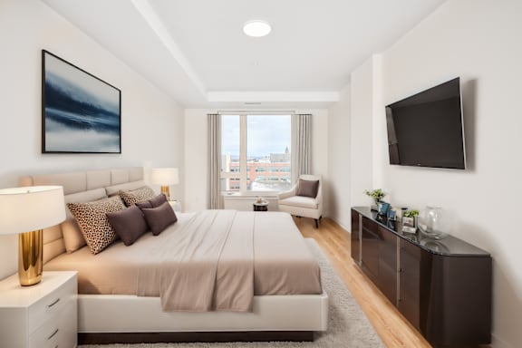 A bedroom with a large bed, a chair, and a painting on the wall.