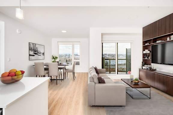 A modern living room with a dining table and a bowl of fruit on the counter.