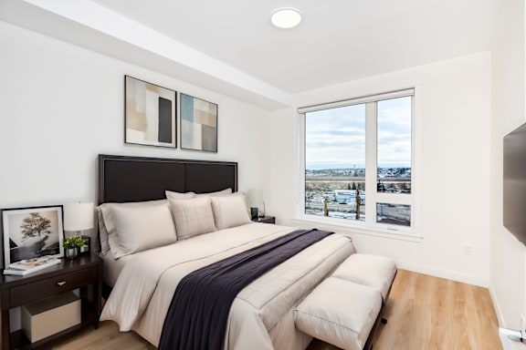 A bedroom with a large bed and a window overlooking a snowy landscape.