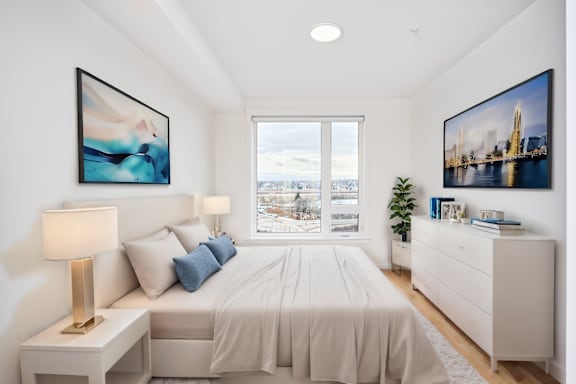 A bedroom with a large bed, two lamps, and two framed pictures on the wall.