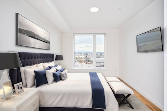 A bedroom with a large bed and a window overlooking a snowy landscape.