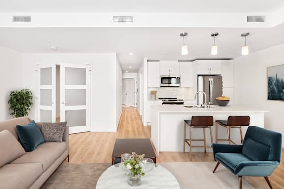 A modern living room with a couch, chairs, and a dining area.