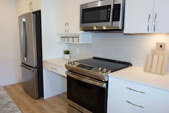 A modern kitchen with a stainless steel refrigerator, microwave, and oven.