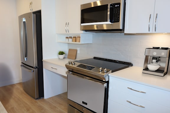 A modern kitchen with a stainless steel refrigerator, microwave, and oven.
