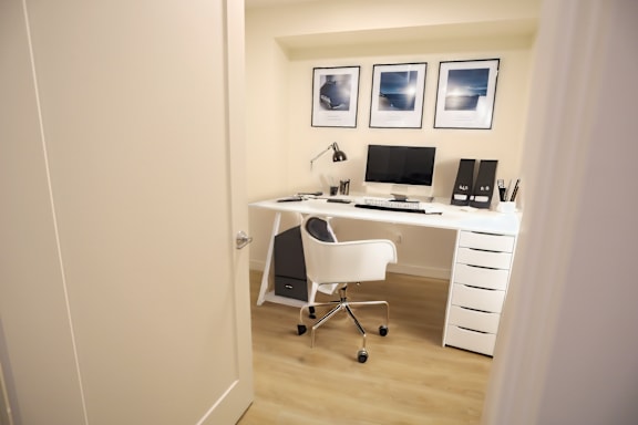 A white chair is in front of a desk with a computer and other items.