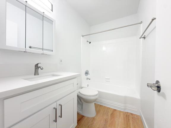 A white bathroom with a toilet, sink, and shower.