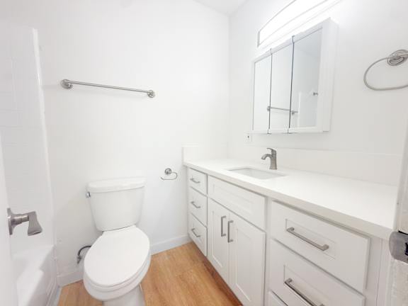 A white bathroom with a toilet, sink, and mirror.