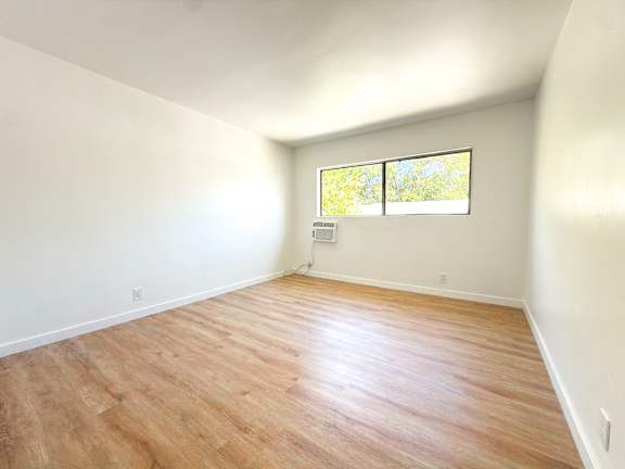 A room with wooden flooring and a window.