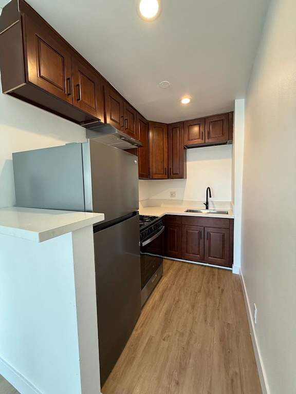 A kitchen with wooden cabinets and a black refrigerator.