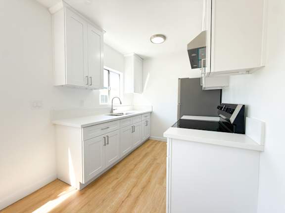 A kitchen with white cabinets and a black oven.