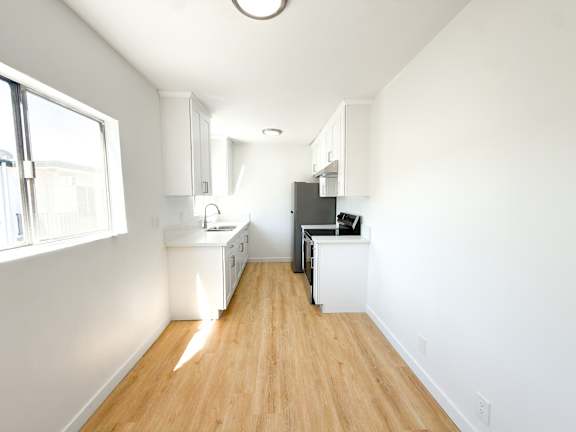 A kitchen with white cabinets and a wooden floor.