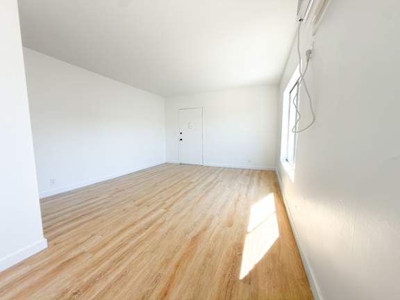 A room with wooden flooring and white walls.