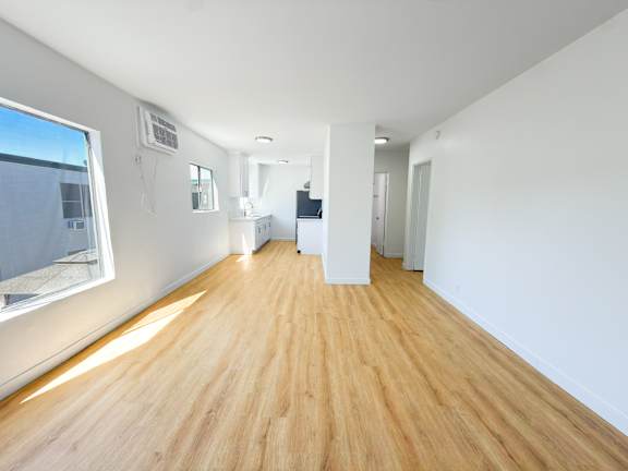 Floor Plan  A long, empty hallway with wooden floors and white walls.