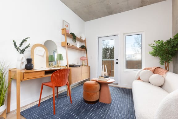 a living room with a white couch and a desk with a chair