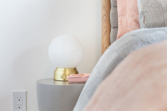 a lamp on a night stand next to a bed