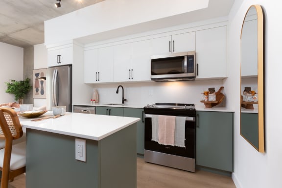 a kitchen with green cabinets and a white counter top and a stove and microwave