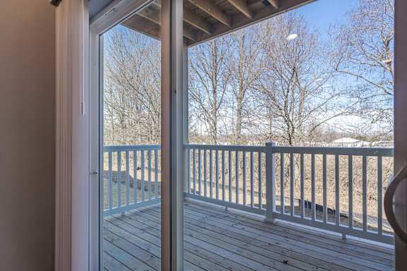 A view from inside a house looking out to a deck with a white railing.