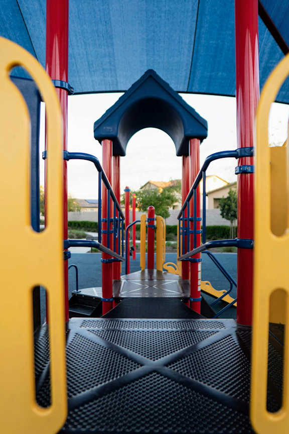 A playground slide with a blue canopy and red and yellow safety barriers.