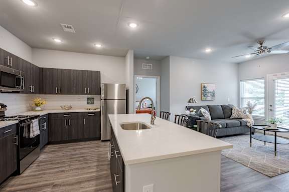 A modern kitchen with dark brown cabinets and stainless steel appliances.