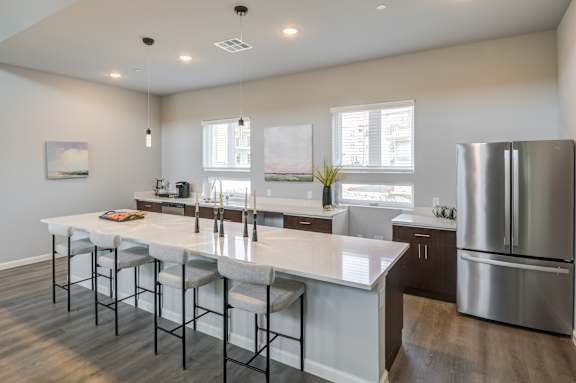 an open kitchen with a large island and stainless steel refrigerator