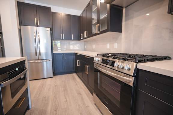 A modern kitchen with black cabinets and stainless steel appliances.at The Franklin at Westfield, Westfield New Jersey