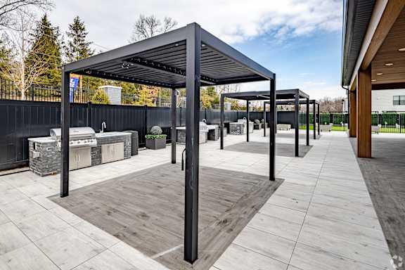 A modern outdoor seating area with a black metal roof and wooden flooring.