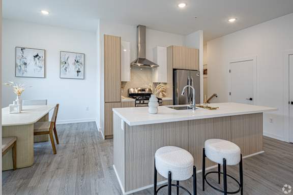 A modern kitchen with a bar stool and a dining table.