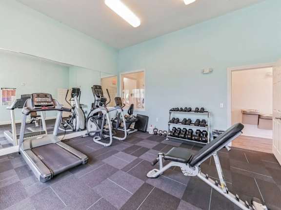 A gym with treadmills, exercise bikes, and dumbbells.