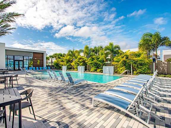 a swimming pool with chaise lounge chairs and a blue sky at Elements on Third Apartments, St. Petersburg