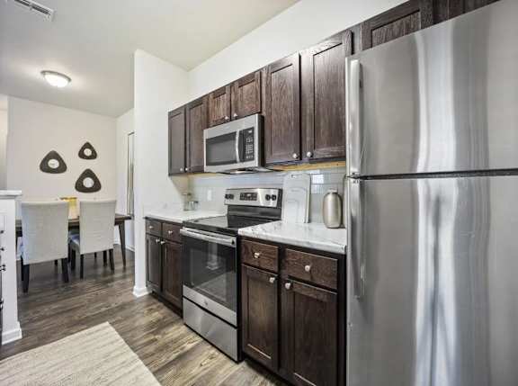 A modern kitchen with dark wood cabinets and stainless steel appliances.