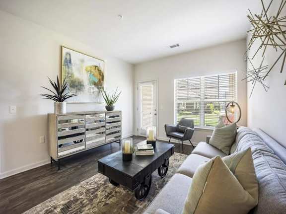 A living room with a grey couch, a black coffee table, and a large painting on the wall.