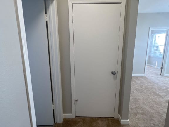 a closet with a door open to a room with a window
