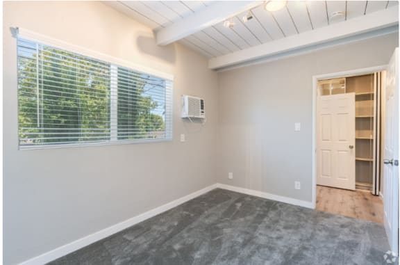 an empty room with a window and a closet