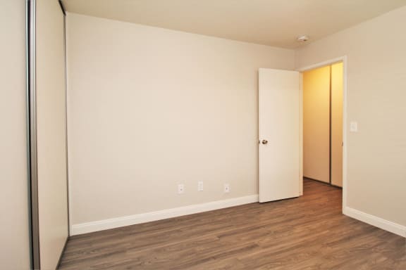 an empty room with wood flooring and a door to a closet