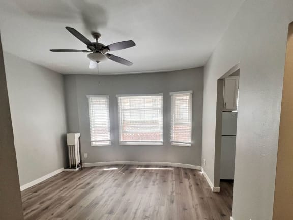 an empty living room with a ceiling fan and windows