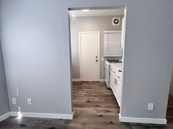 a renovated kitchen with white cabinets and a wood floor