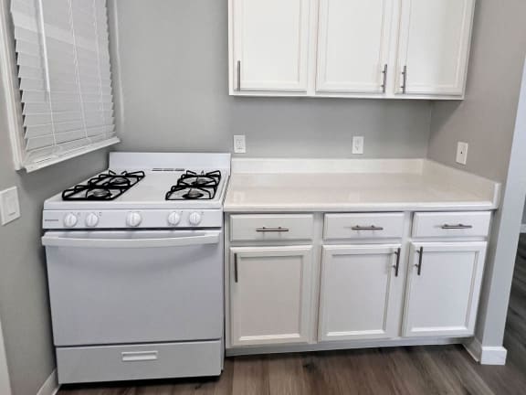 a kitchen with white cabinets and a stove and a counter