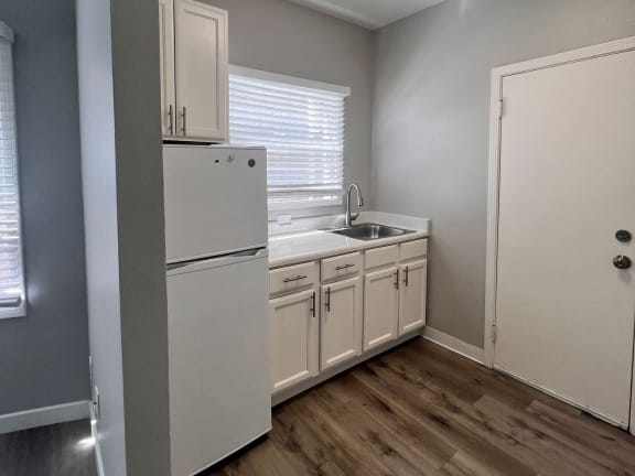 a kitchen with white cabinets and a sink and a refrigerator