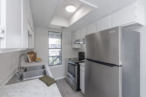 A kitchen with a stainless steel refrigerator, oven, and sink.