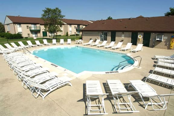 an outdoor swimming pool with white chairs around it